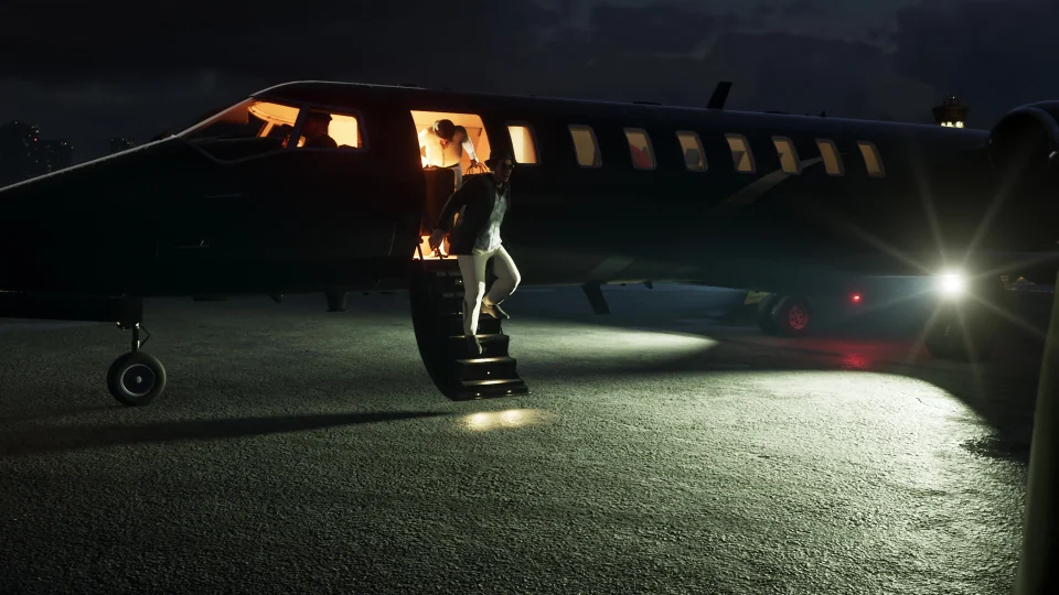 Un hombre baja por la escalerilla iluminada de un avión privado a la plataforma nocturna