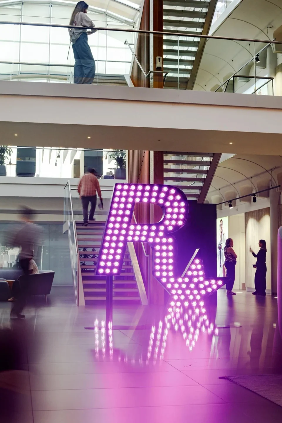 Rockstar North atrium with a staircase, people and a large pink Rockstar sign