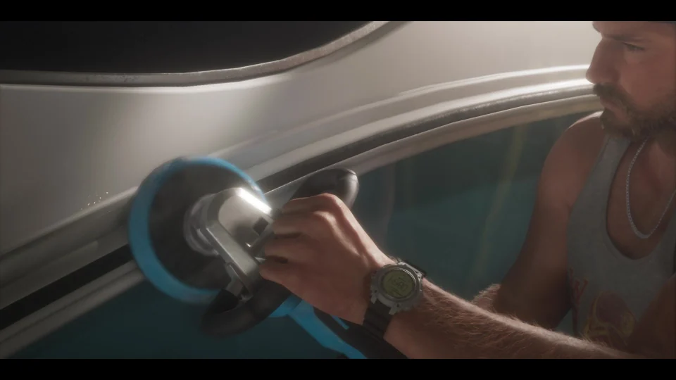 Jason holds a polishing machine beside the hull of a boat