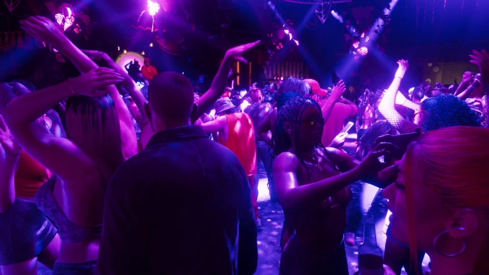 Personas bailando en una discoteca bajo luces violetas y rosas