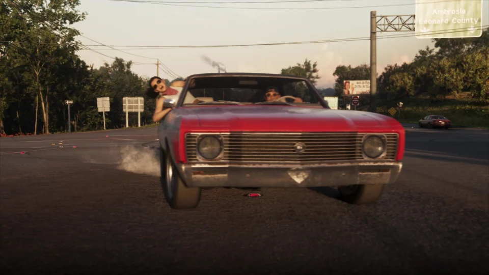 Jason and Lucia in a red classic car with a broad grille and round headlights